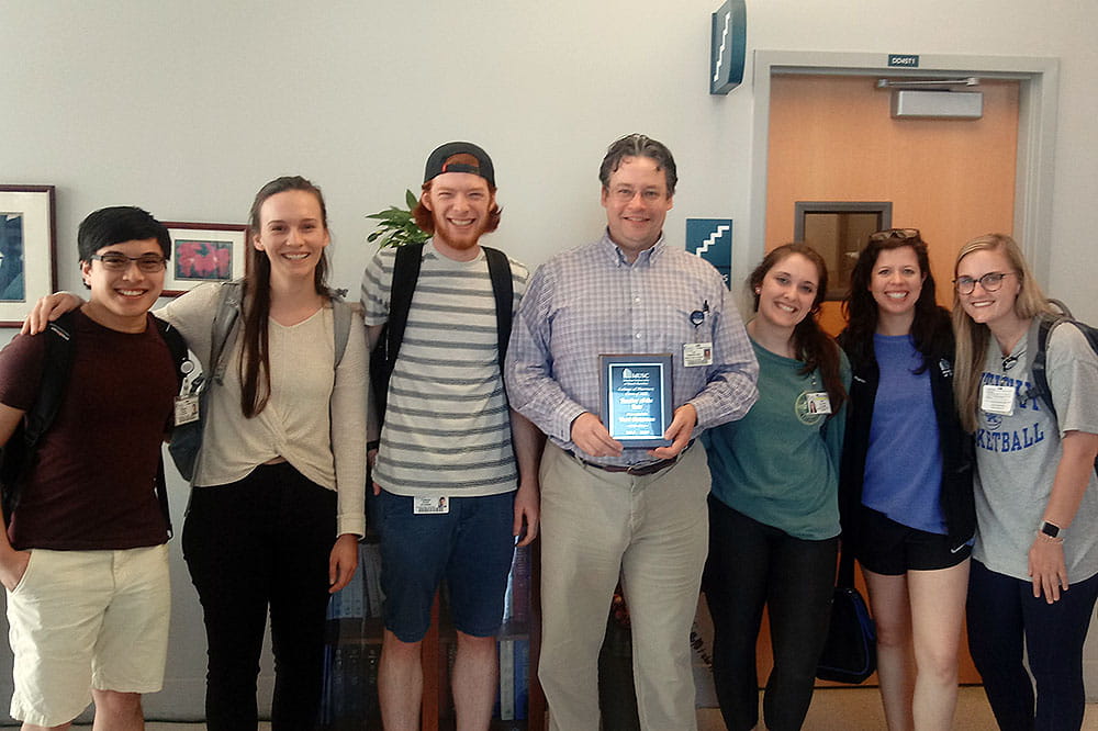 Dr. Yuri Peterson, center, with College of Pharmacy students. He was awarded teacher of the year in 2019. Photo provided