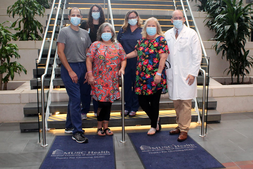 a group of people wearing masks poses in front of a staircase