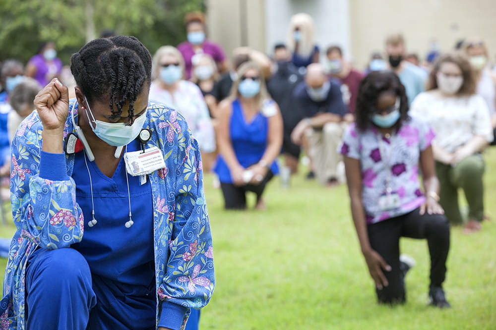 Nurse Narkarsha Prioleau kneels for 8 minutes and 46 seconds, the length of time George Floyd lay dying under a white policeman's knee. Photos by Sarah Pack