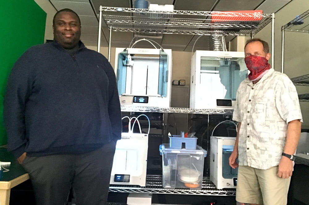 Lemon and Paggi pose in front of 3D printers