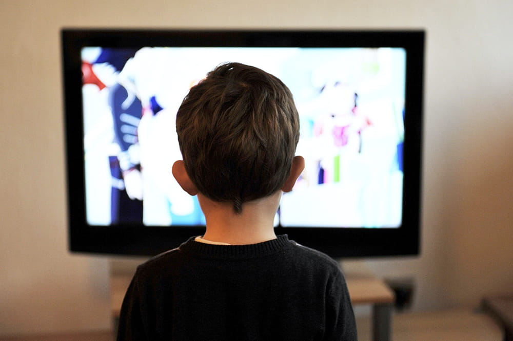photo of the back of a young boy's head watching TV