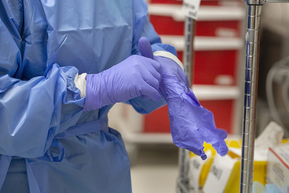 closeup photo of a nurse putting on double layers of medical gloves