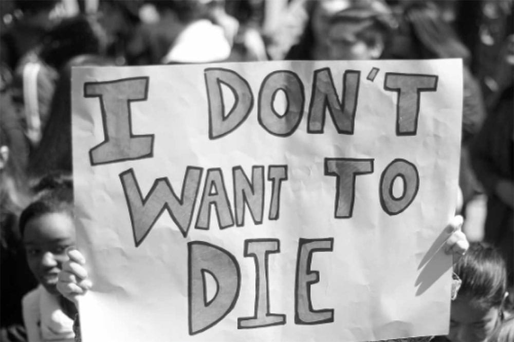 People holding sign that says I don't want to die