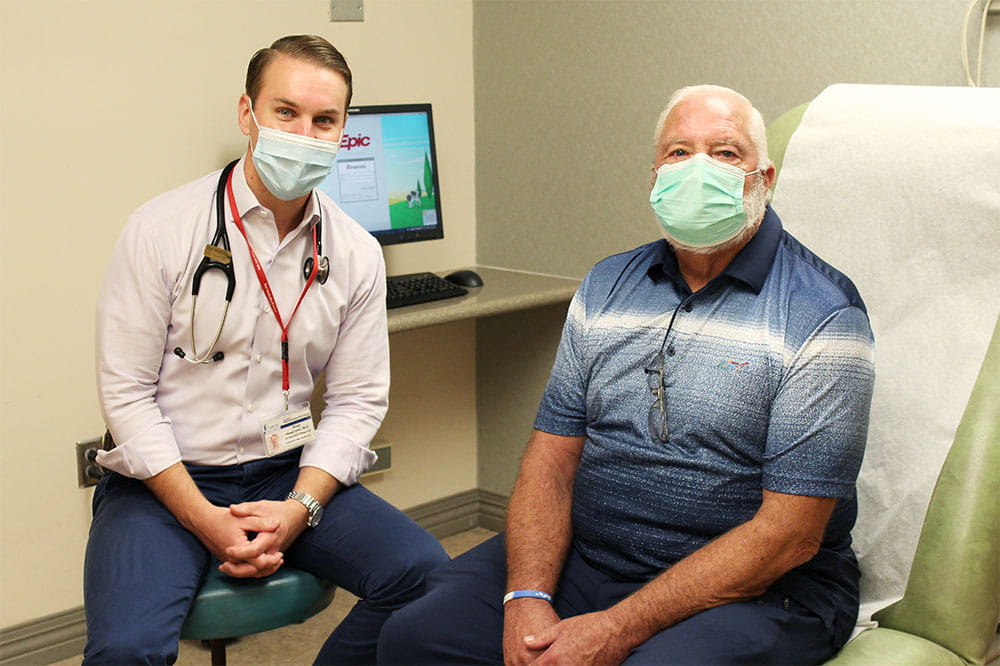 Dr. Brian Greenwell and Samuel Jackson sit in an exam room with masks on