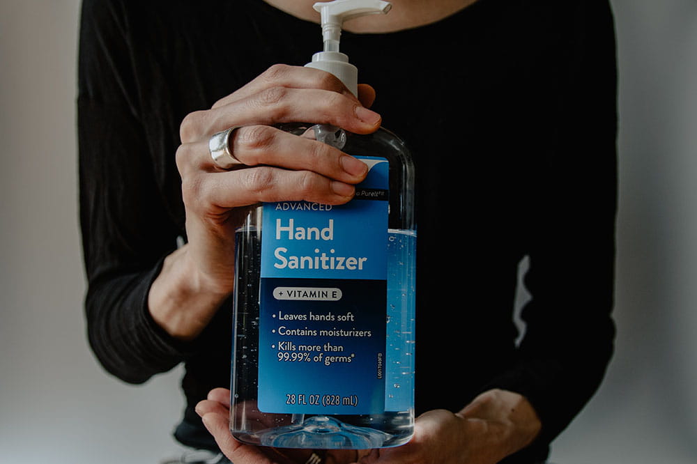 Woman holding large container of hand sanitizer.