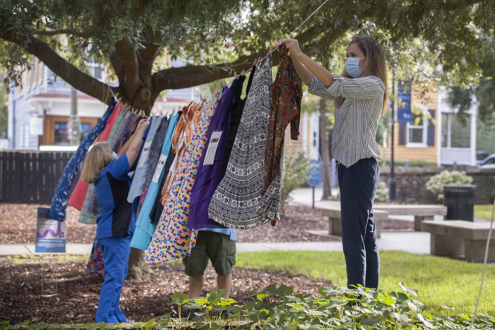 Karen Hughes and Abby Steere-Williams hang clothing on the MUSC Horseshoe.