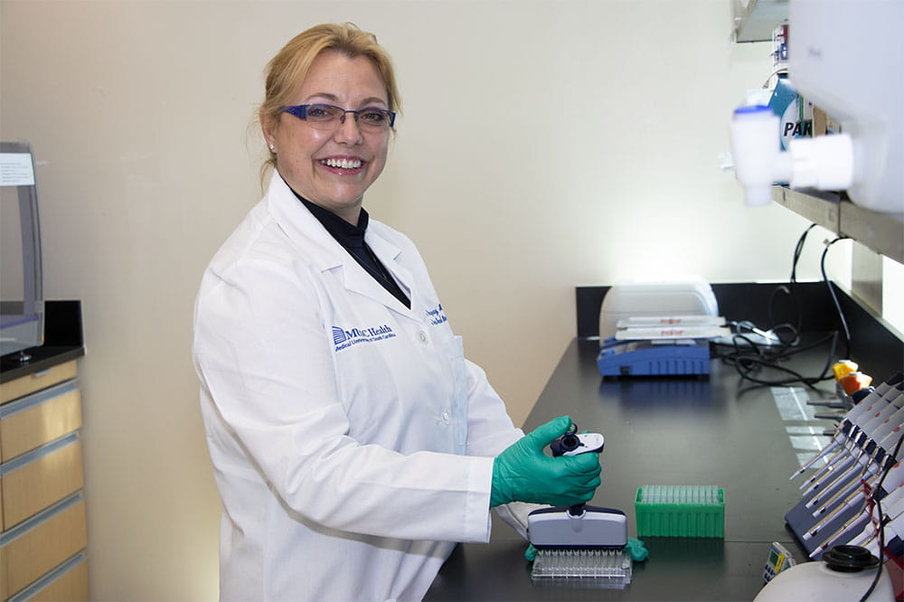Dr. Sophie Paczesny stands at a counter in her lab and works with test tubes
