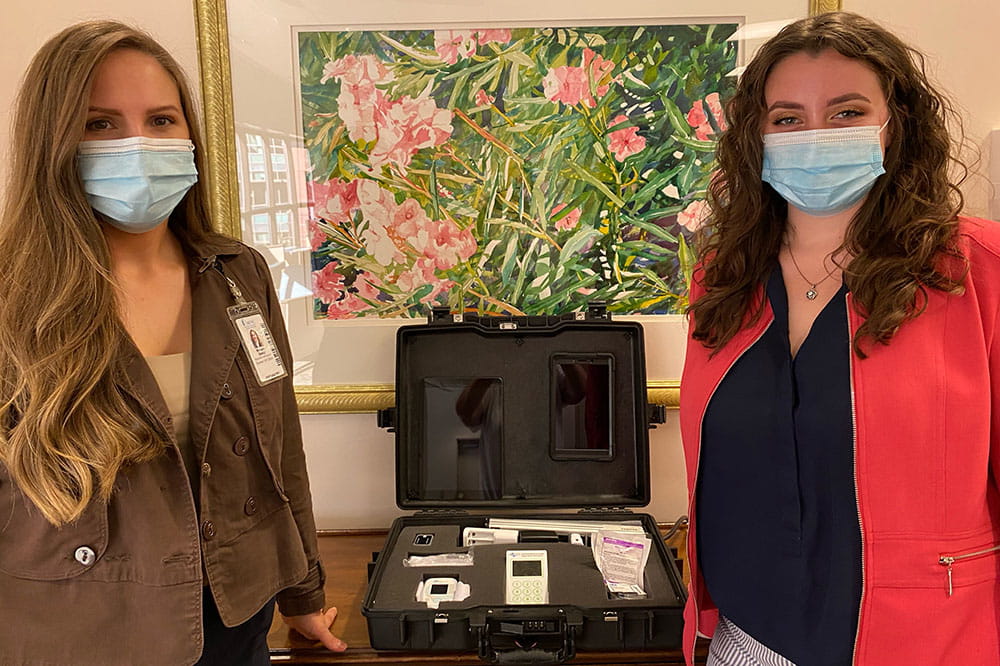 Morgan Maddox and Sarah Huffman hold neuroCOVID device