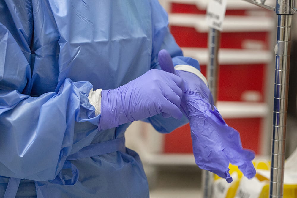 close up of a nurse in PPE donning gloves