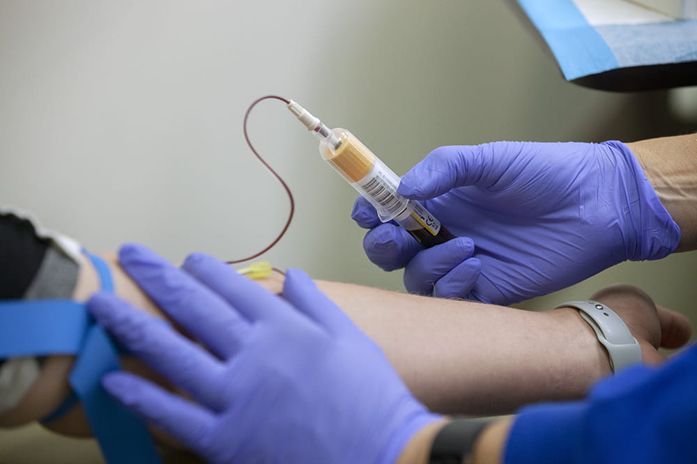 Closeup of Kelly Warren's arm as her blood is drawn during a COVID-19 vaccine trial.