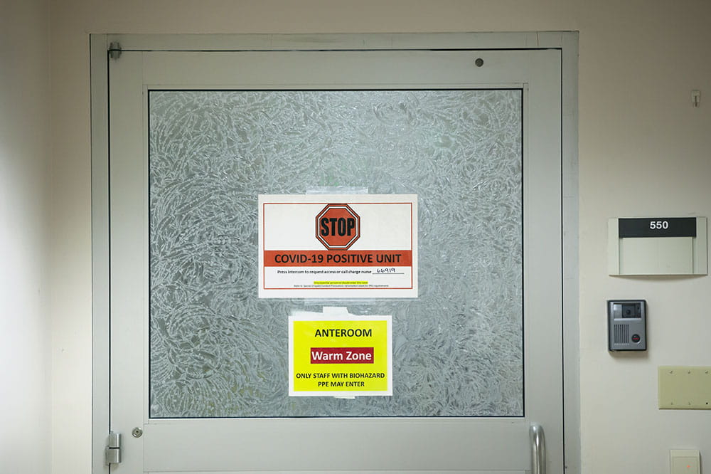 Signs on a door saying it Is a COVID unit.