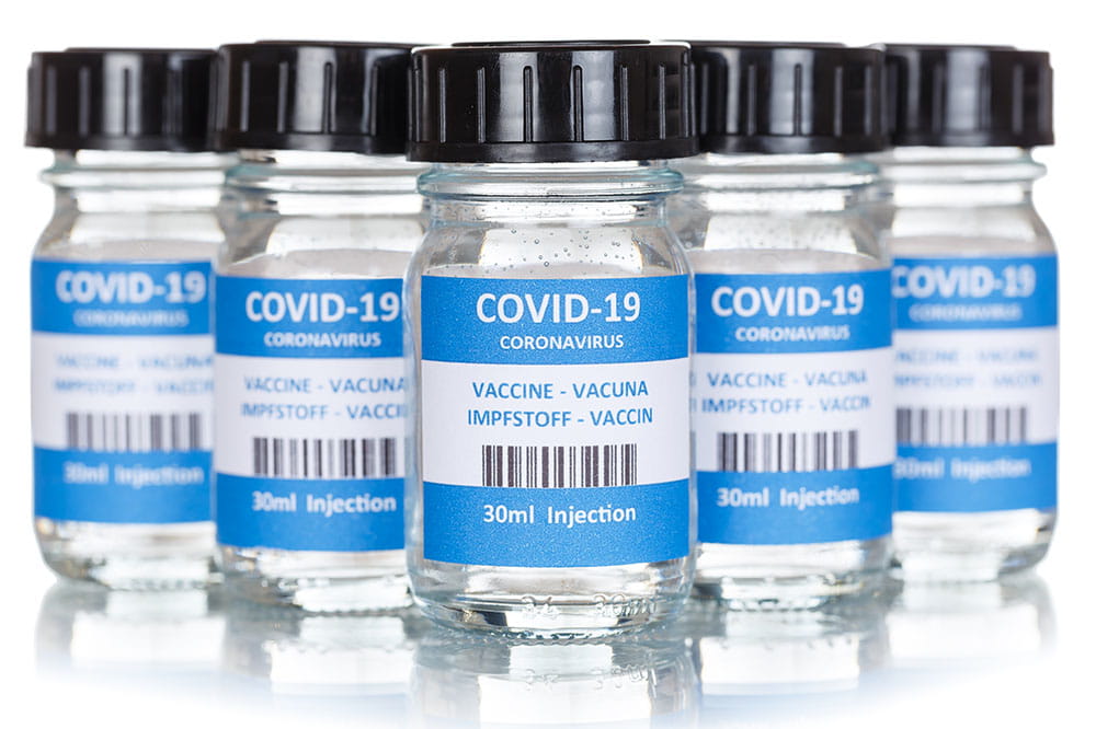 five vials of Covid-19 vaccine on a white surface