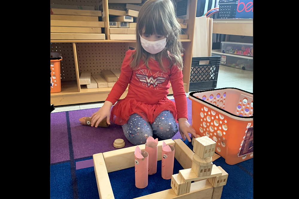 Girl wearing a mask plays with blocks.
