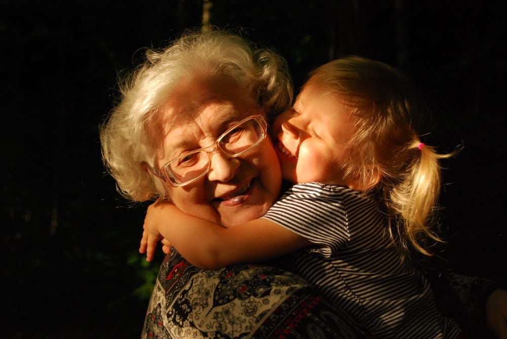 A grandmother being hugged by her granddaughter