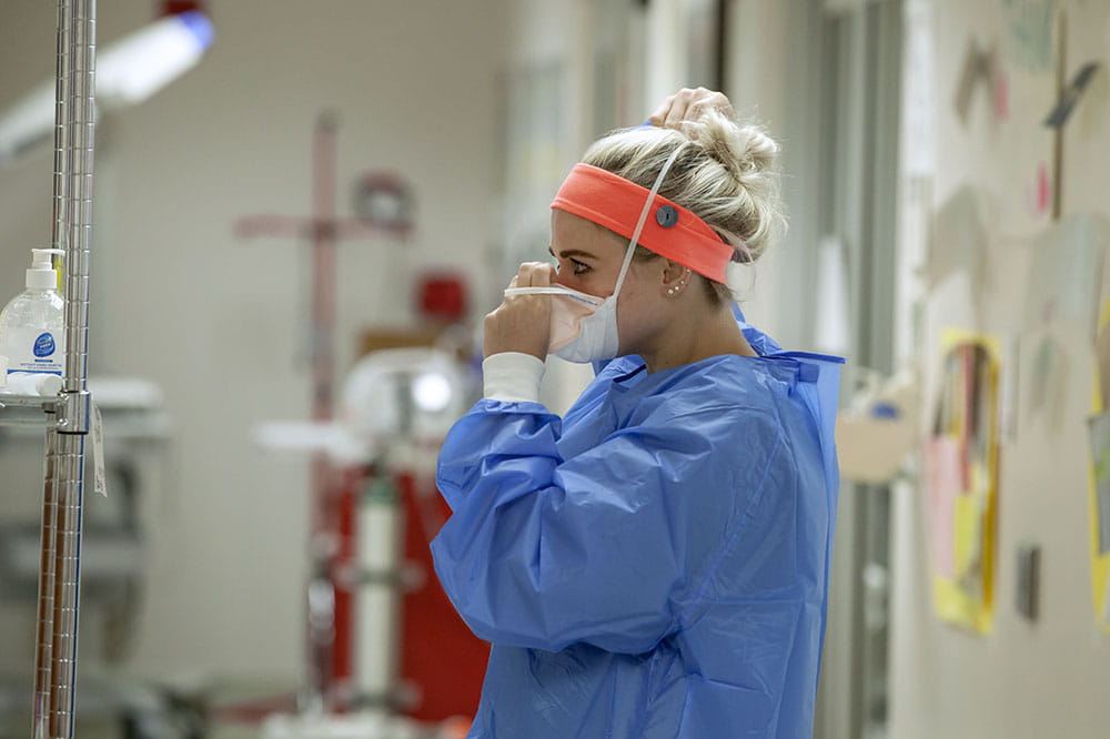 MUSC nurse Rebecca Hale puts on PPE prior to going into a patient’s room.