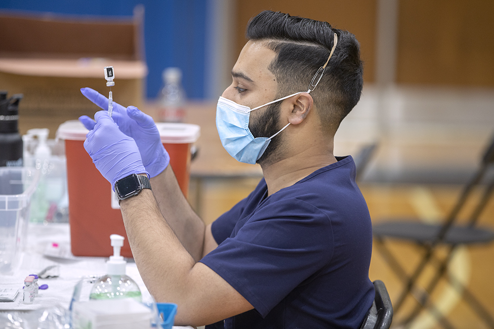 MUSC clinical pharmacist Joseph Xavier reconstitutes the Pfizer Covid-19 vaccine to give to students at R.B. Stall High School.