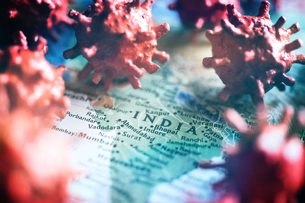 Map of India with coronavirus particles resting on top of it.