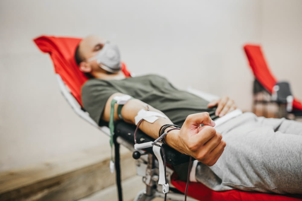 a man lying down squeezing his fist as he gives blood