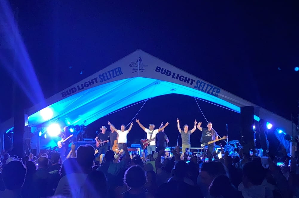 Group of musicians, including Darius Rucker, on a stage at night with blue glowing lights around them