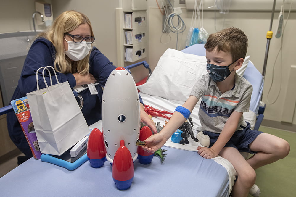 Senior child life specialist Jennifer Redfern works with Ethan Appleby while he waits to get his first dose of the Moderna vaccine.