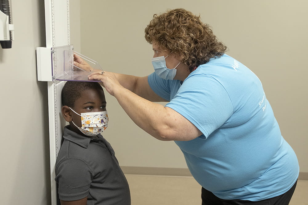 Nurse Karen Hawkins checks Nolan Rivers' height. Nolan is participating in the Moderna vaccine dosing trial for children.