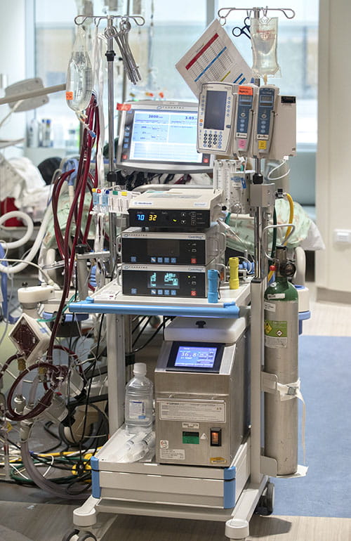 ECMO cart, which has a lot of tubes and wires, in a child's hospital room.