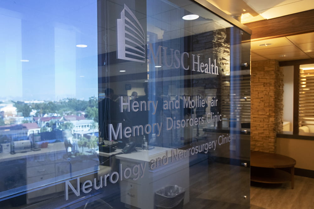 The Charleston peninsula is visible beyond an etched glass wall with the name of the Henry and Mollie Fair Memory Disorders clinic