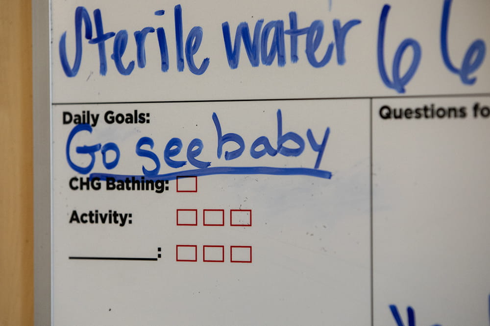 Whiteboard with the words Go see baby as a daily goal.