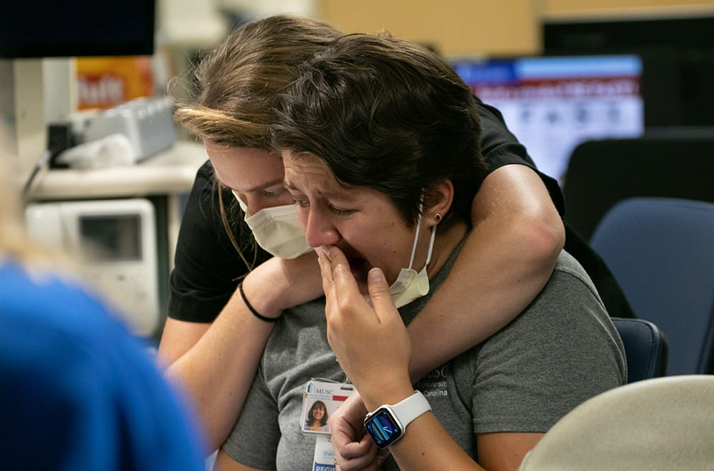 Deux infirmières qui viennent d'appeler le conjoint d'un patient pour lui faire savoir qu'il était sur le point de mourir se consolent en pleurant