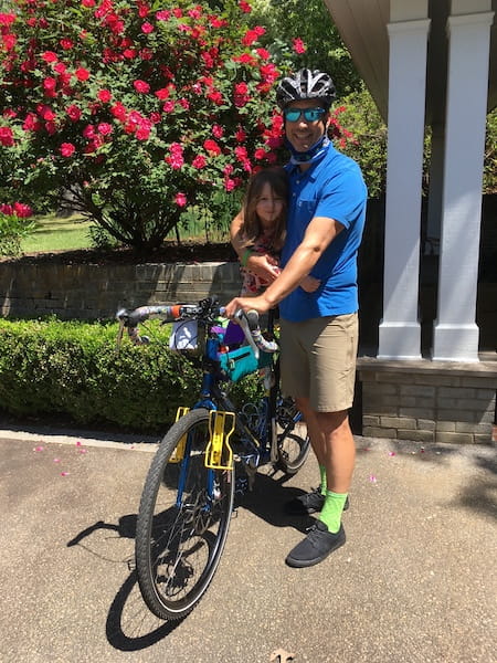 Sutton standing next to his bike with his daughter