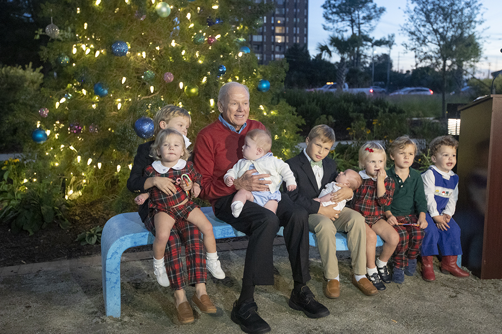Charles Darby with children at Angel Tree lighting sitting in front of tree.