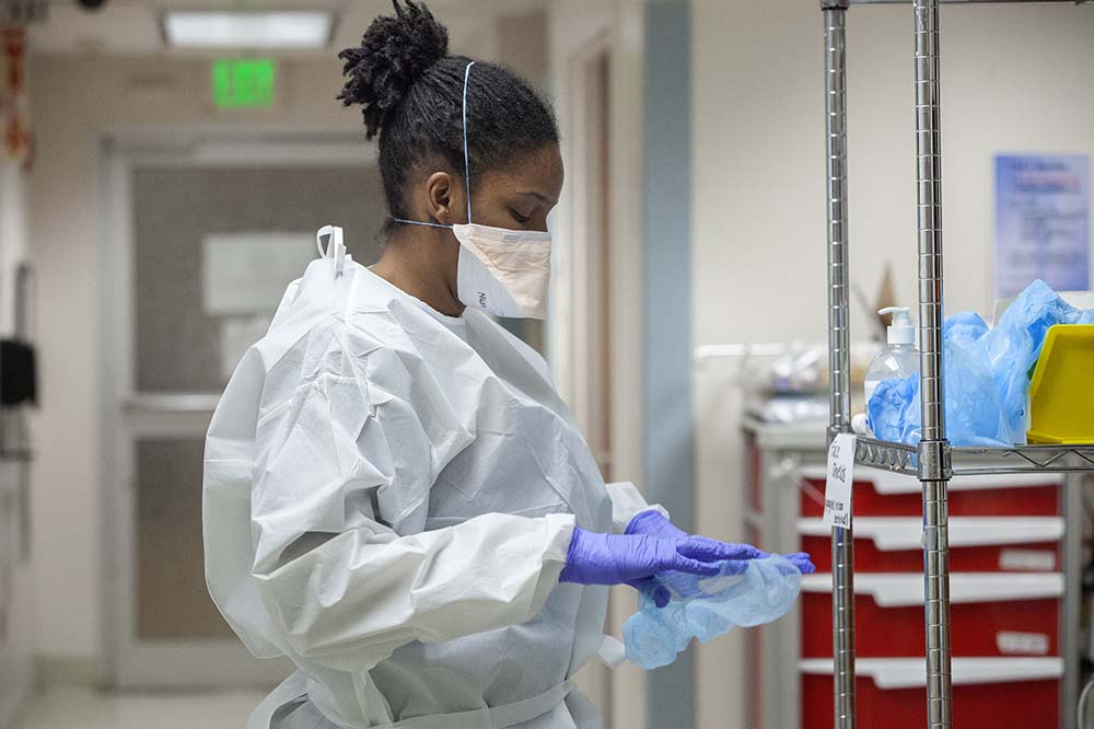 Erica Tollerson, RN, puts on personalal protective equipment so that she can care for covid-19 patients at unit 5C at the main hospital.