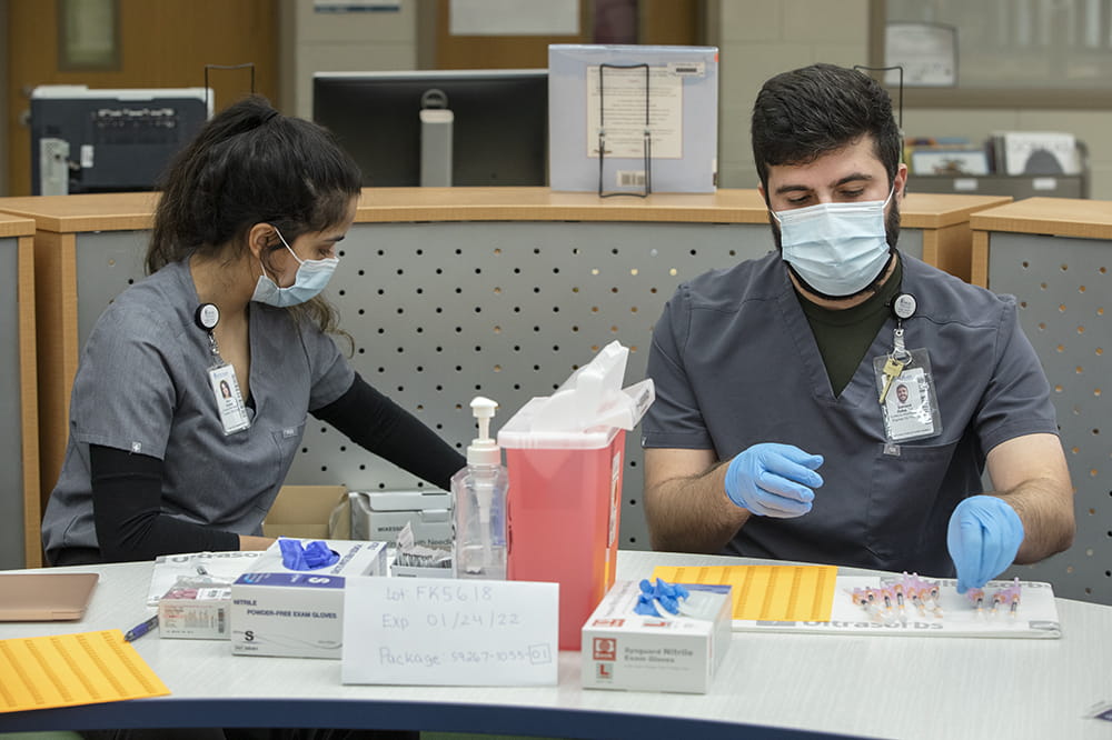 College of Pharmacy student Sana Dossaji and clinical pharmacist prepare vaccines for children at E.B. Ellington Elementary School.