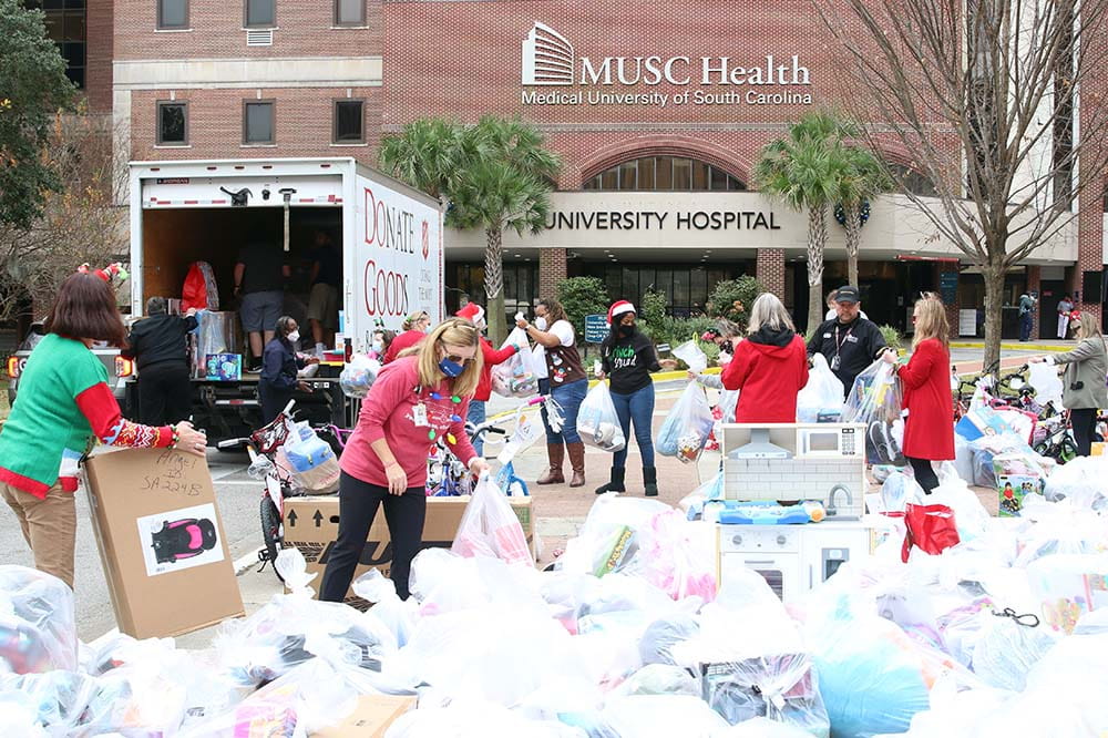 People load bags of Angel Tree gifts into a Salvation Army Truck in front of an MUSC Health building.