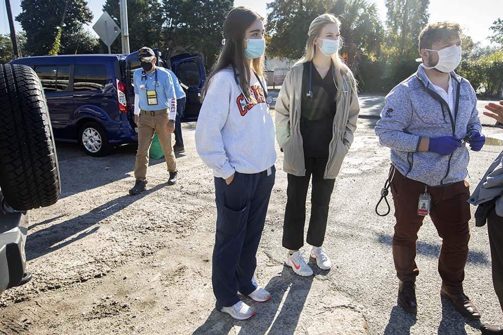 Medical students Anna Beth Eitel, left, and Cora Bisbee listen while Dr. Thomas Ricks talks with a homeless man. Allan Woods is walking up behind them.