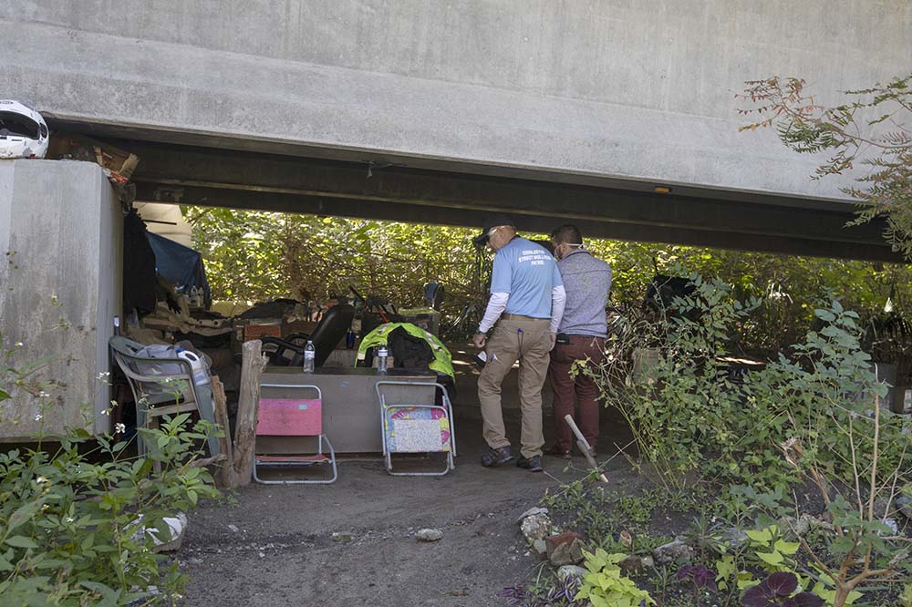 Allan Woods and Dr. Thomas Ricks look at a homeless camp to see if anyone is present.