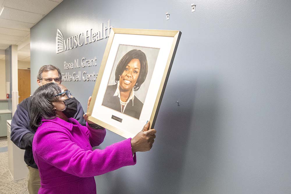 Laura Grant hangs a photo of her daughter in the Rena N. Grant Sickle Cell Center.