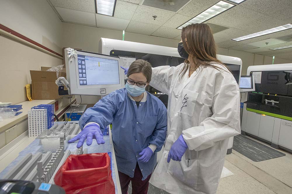 Glenda Rebl, lab technician, right, and Katlin Thompson, lab associate, prepare samples to run in the Abbott Alinity machine to test them for covid.