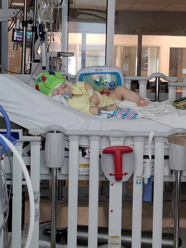 a baby lies on his side in a hospital bed