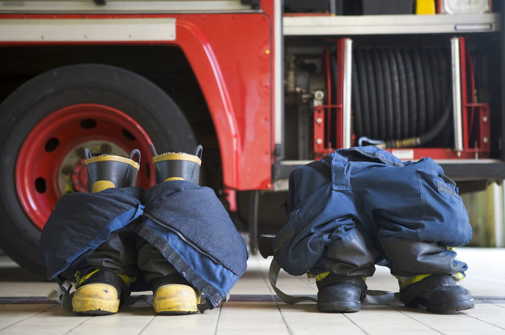 Two empty pairs of fire boots in front of a fire truck