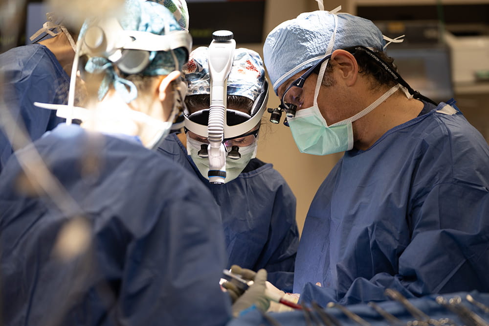 Dr. Jason Newman and three other care team members perform a head and neck cancer surgery