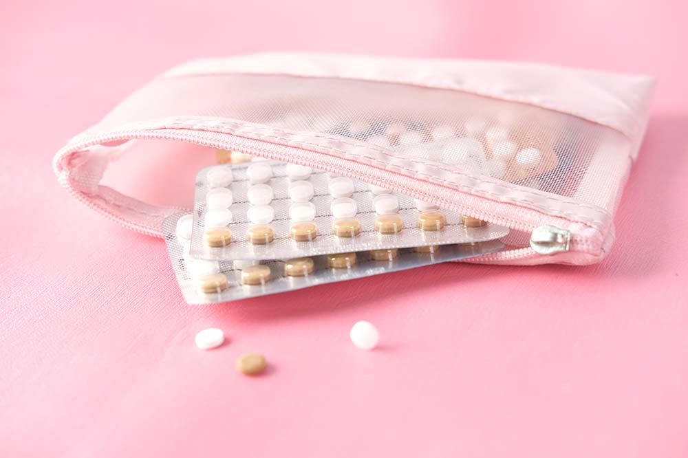 pink birth control pills on a pink background