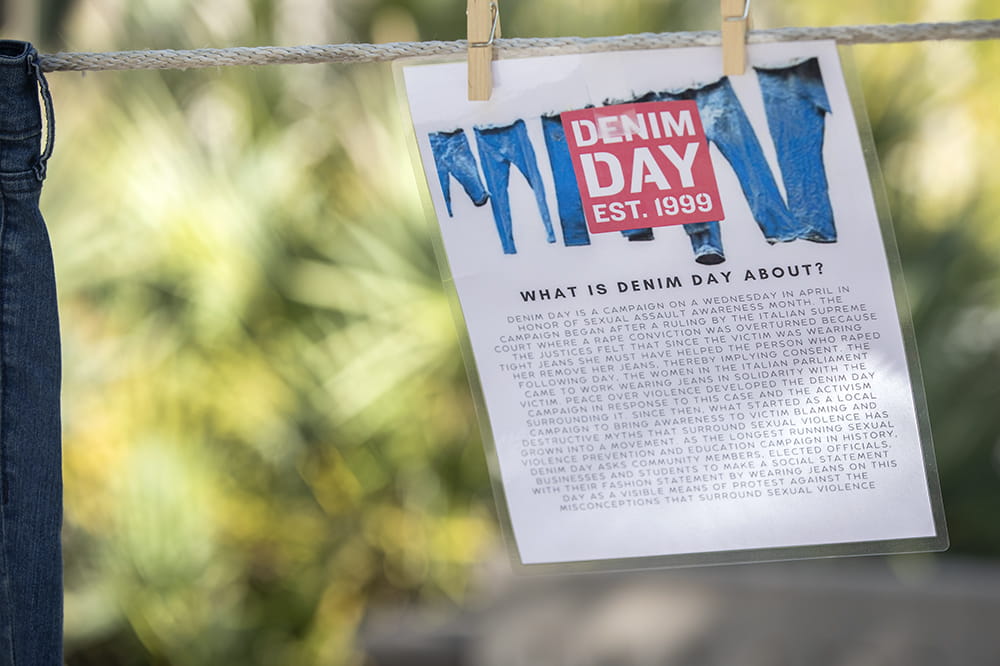 A laminated piece of paper clipped to the clothesline explaining the meaning of denim day