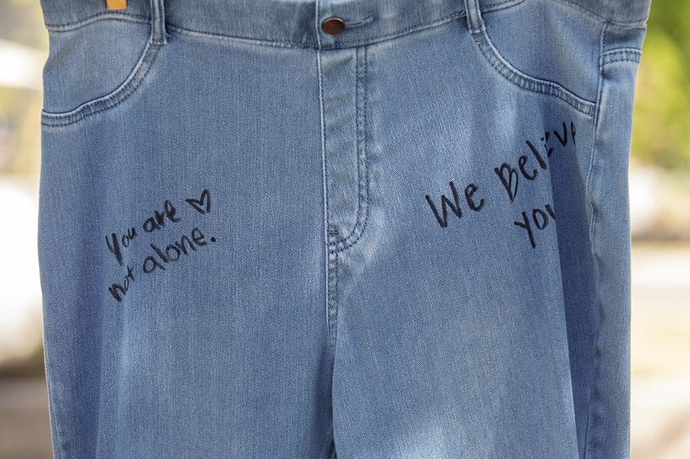 Close up shot of jeans with a handful of messages written on them like you are not alone