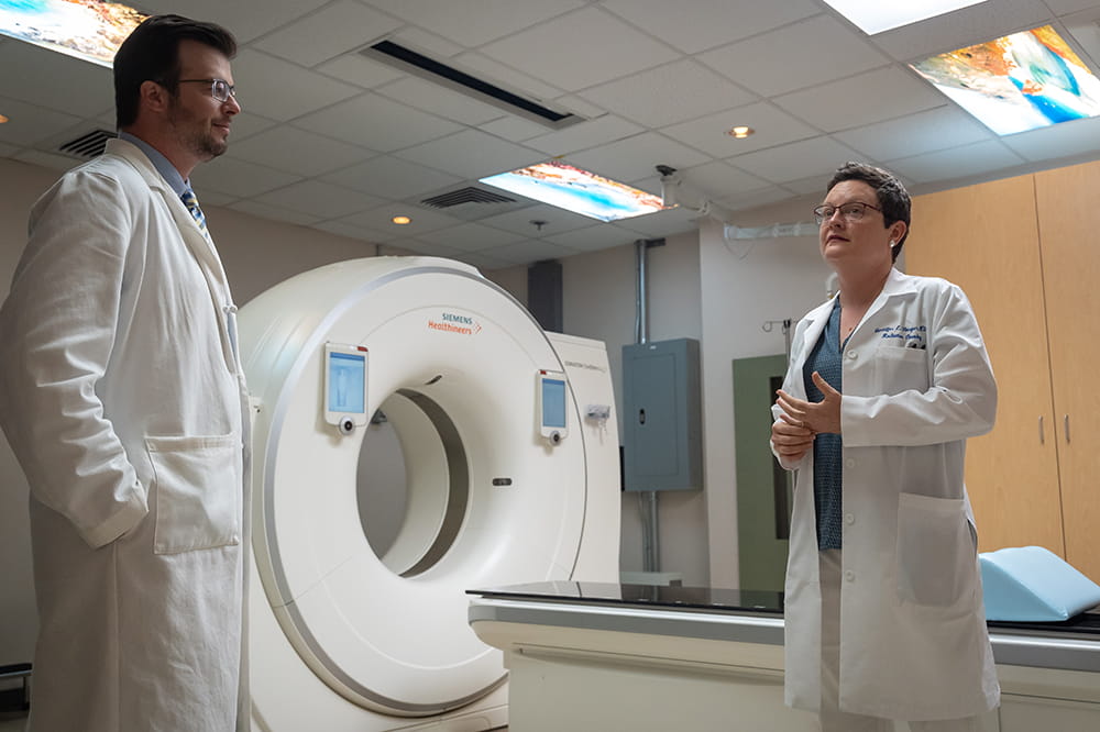 Dr Jennifer Harper, right, speaks with a resident with a CT scanner in the background