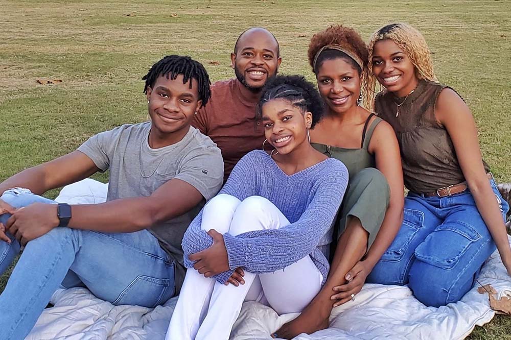 Kira Adkins and her family pose outside on a grassy lawn. From left to right: Kira's brother Dyran, her father Randy, her sister Kayla and her mother Sherlonda.