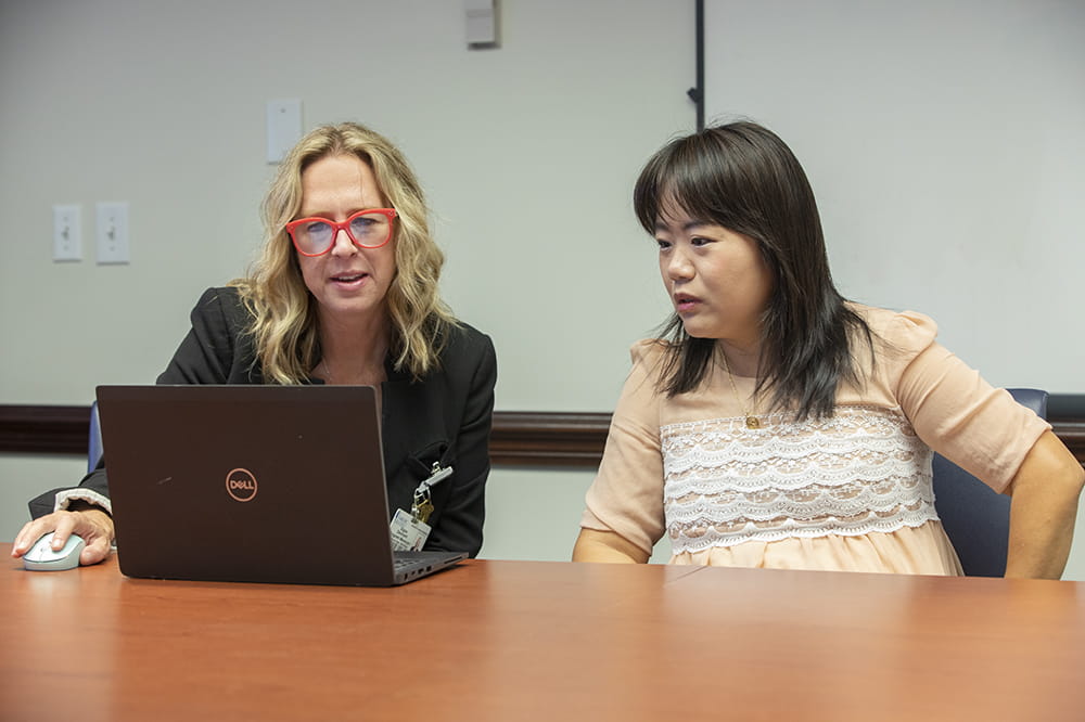 Signe Denmark of the Office of Clinical Research and Wenjun He of the Biomedical Informatics Center looking at clinical trial data on a computer