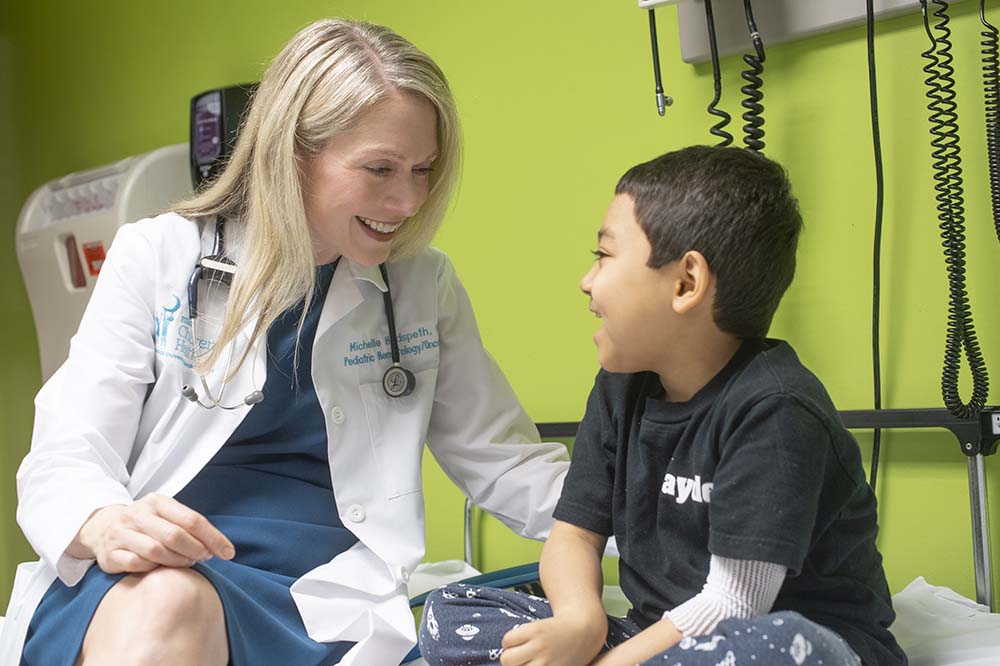 Dr. Michelle Hudspeth talks with a child.  They are both smiling.
