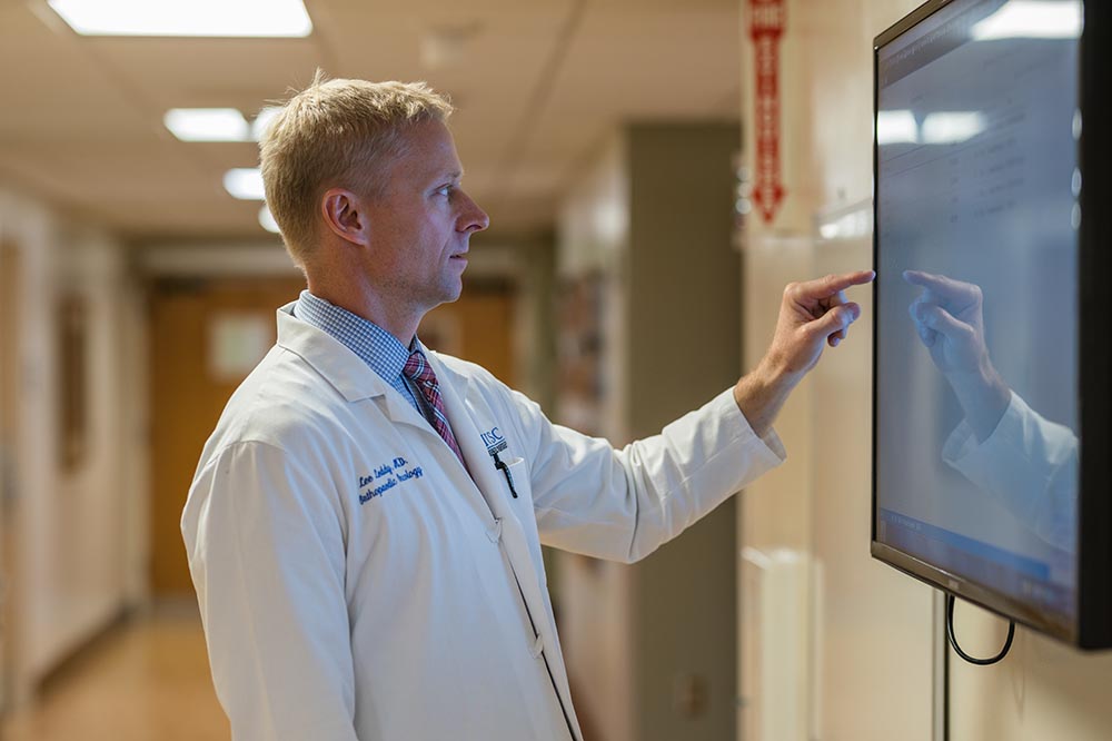 a doctor looks at a large screen in a hallway