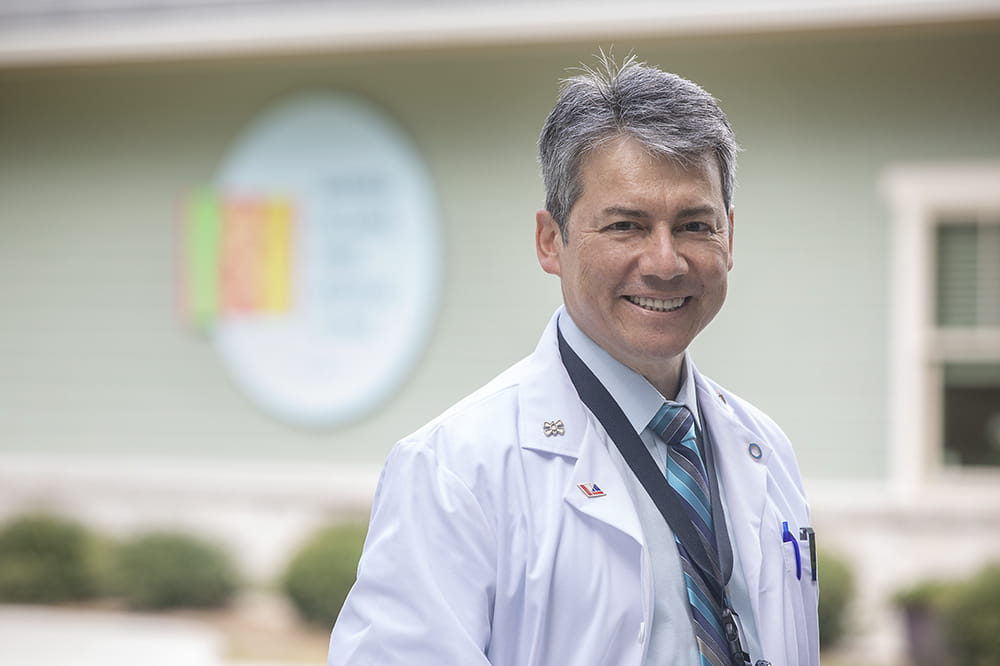 Dr. Hermes Florez smiles while wearing a white doctor's coat.